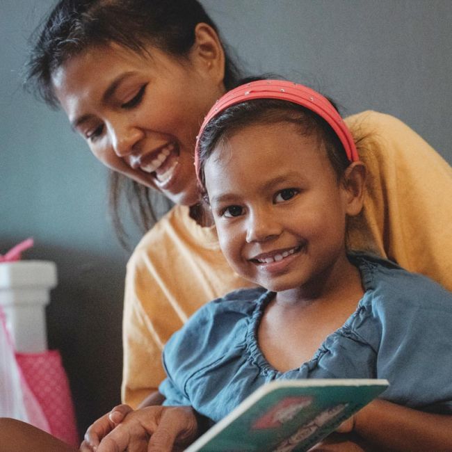 girl reading book with adult